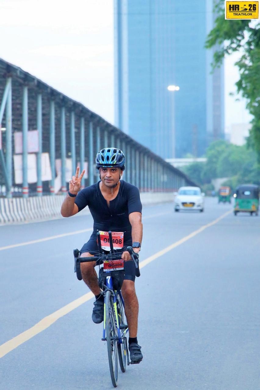 Vivek Sharma giving a peace sign on the bike at HR26 Duathlon