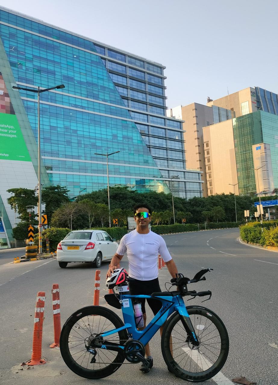 Vivek Sharma standing with his time trial bike, training for Ultraman 2027
